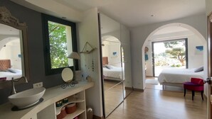 Une chambre moderne avec un grand miroir, une table de chevet avec une lampe et un fauteuil rouge.