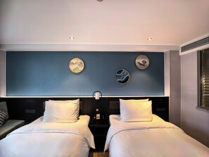 Habitación de hotel con dos camas, una mesita de noche, teléfono en la pared y decoración mural.