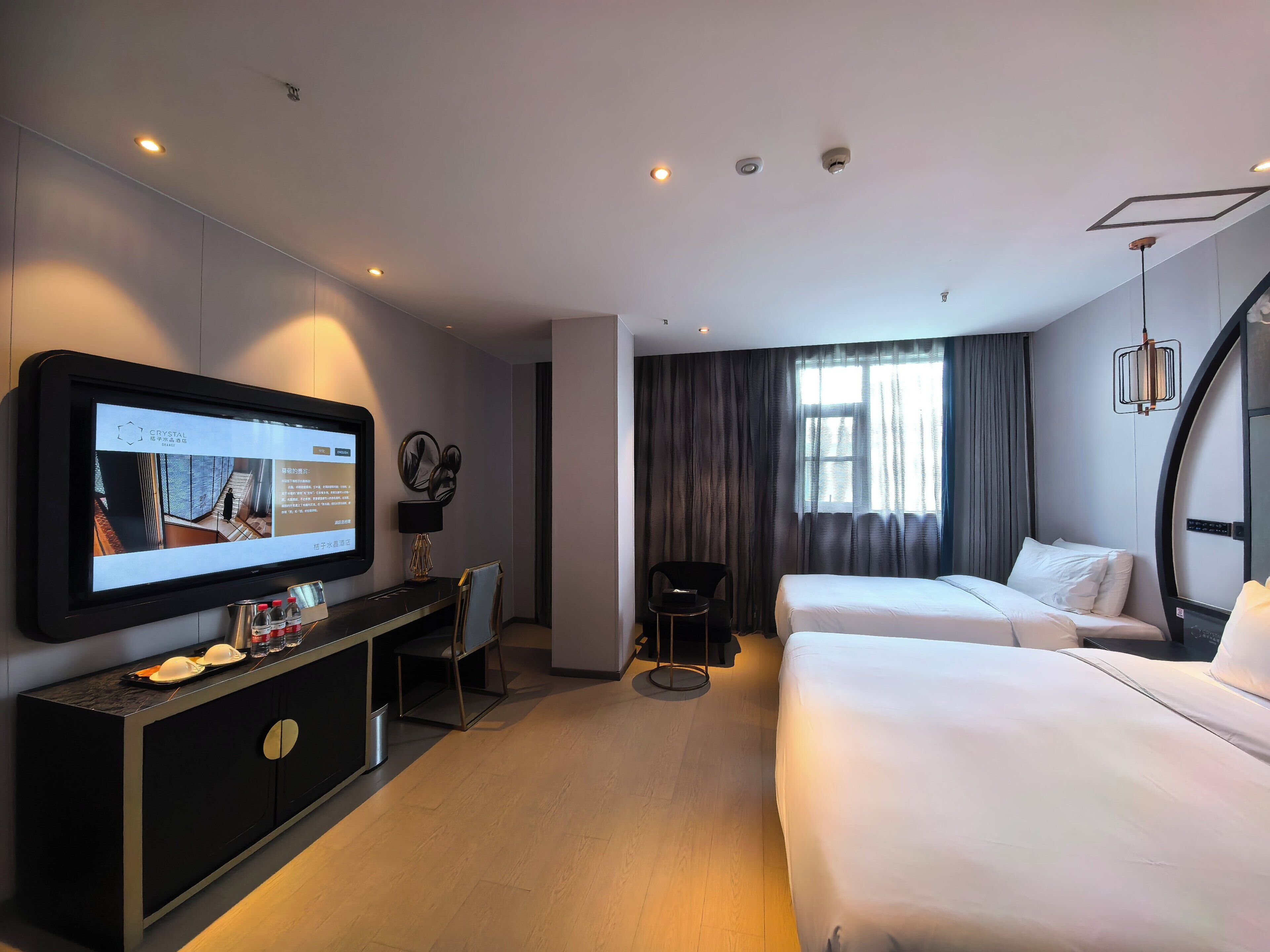 Habitación de hotel con cama, escritorio con computadora, televisor y ventana con cortinas.