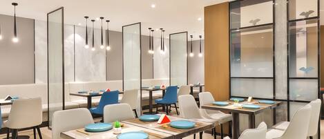 A modern dining area with multiple tables and chairs, featuring a minimalist design with clean lines and a neutral color palette.