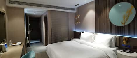 Een hotelkamer met een bed, nachtkastje, bureau, stoel en spiegel.