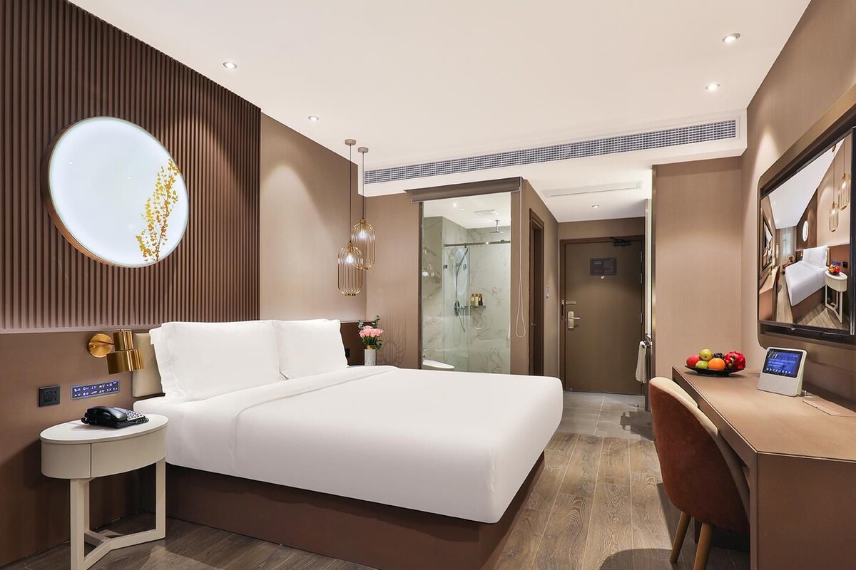Una habitación de hotel moderna con una cama grande, una mesita de noche y un escritorio con una computadora.