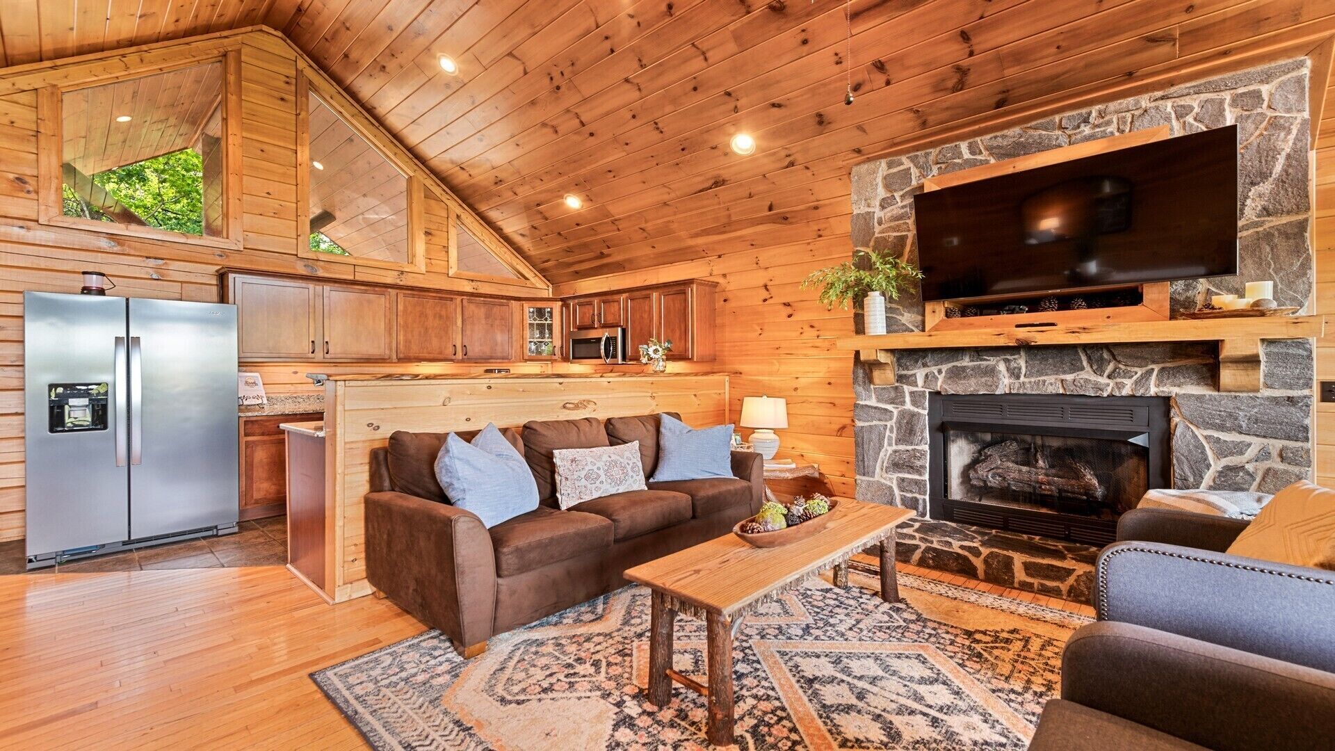 Ein gemütliches Blockhaus-Interieur mit Kamin aus Stein, Holzboden und einer Küchenzeile.