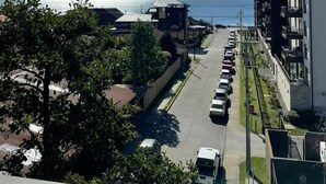 A residential street with parked cars, a clear sky, and a view of the sea in the distance. - Beautiful Apartment With Terrace and Lake View (Puerto Varas)