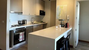A modern kitchen with white cabinets, stainless steel appliances, and a central island. - Beautiful Apartment With Terrace and Lake View (Puerto Varas)