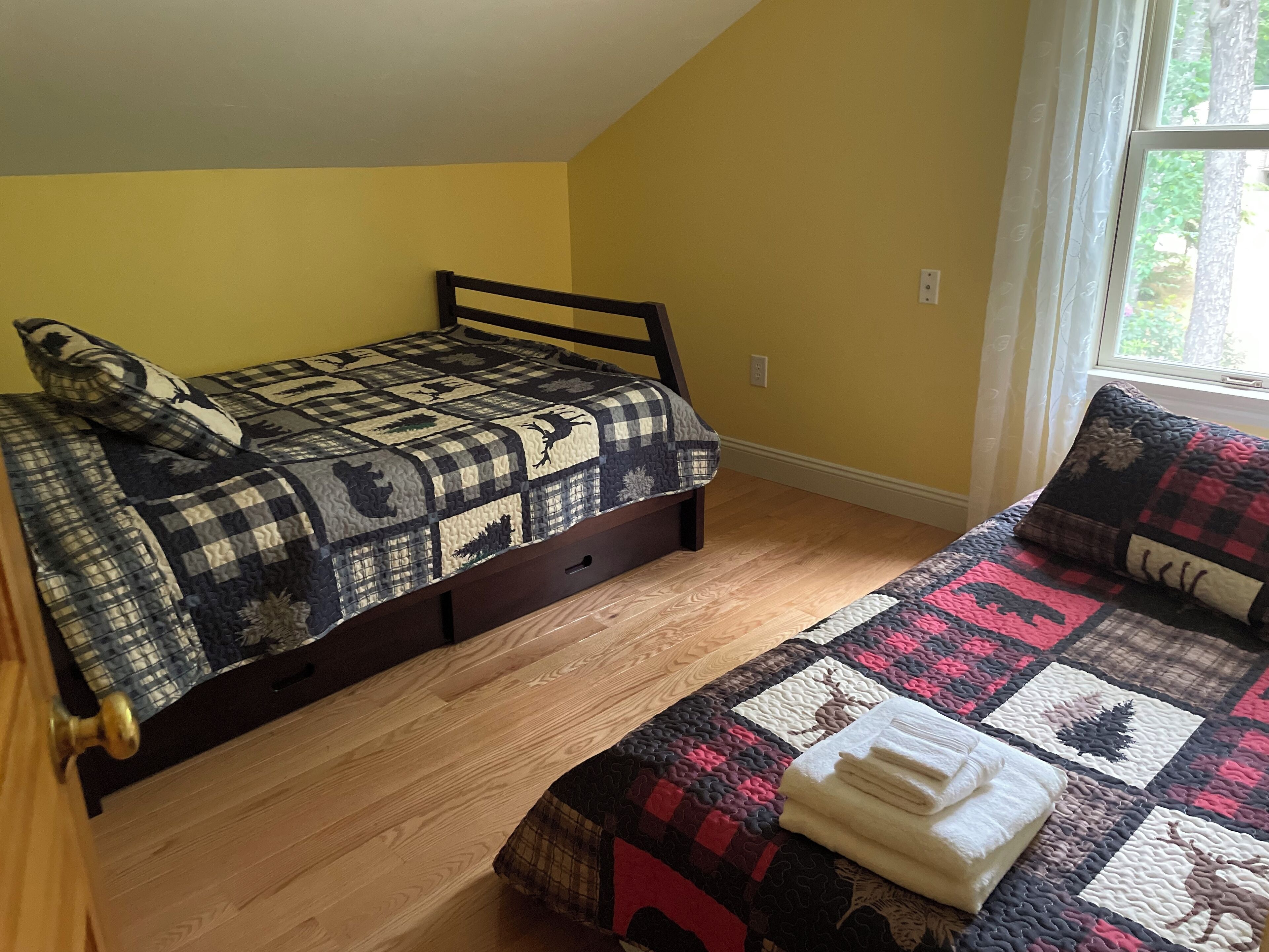 A bedroom with a bed, a window, and a wooden floor.