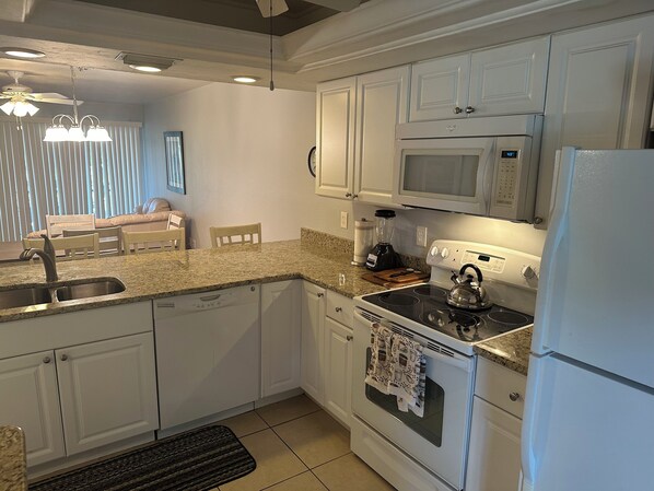 A modern kitchen with white cabinets, a built-in microwave, a stove, and a refrigerator.