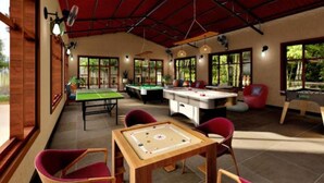 Amplia zona recreativa interior con mesas de billar, futbolín y juego de los palos.