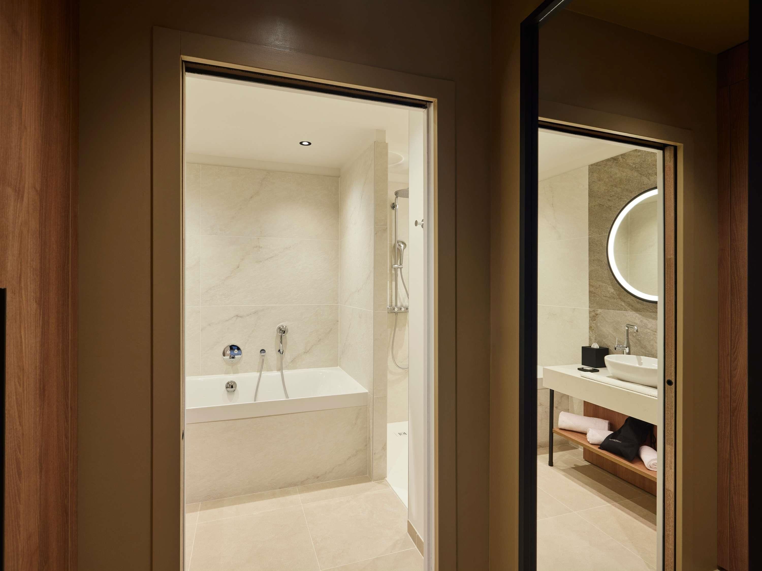 Une salle de bain moderne équipée d’une baignoire, d’une douche et d’un meuble-lavabo avec un miroir.