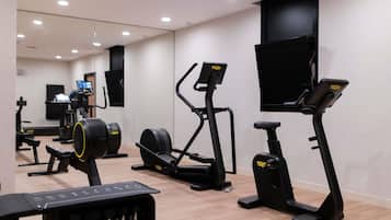 A gym with various exercise machines, a television, and a digital display.