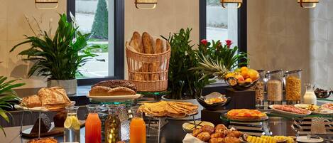 A buffet with various food items, including bread, pastries, and fruits.