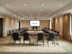 A conference room with a long table, chairs, a projector screen, and a carpeted floor. - Domaine du Liziec Vannes - MGallery Collection (Vannes)