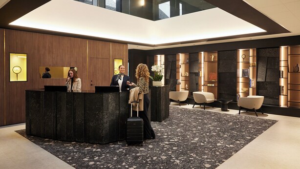 Un moderno vestíbulo de hotel con mostrador de recepción, zona de estar y un gran tragaluz.