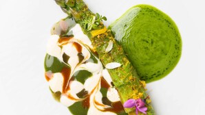 Un plato con espárragos, salsa verde y una cucharada de crema.