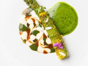 Un plat composé d’asperges, d’une sauce verte et d’une cuillerée de crème.