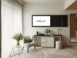 A modern hotel room with a large window, a desk with a laptop, a chair, a small table with a vase of flowers, and a large mirror. - Domaine du Liziec Vannes - MGallery Collection (Vannes)