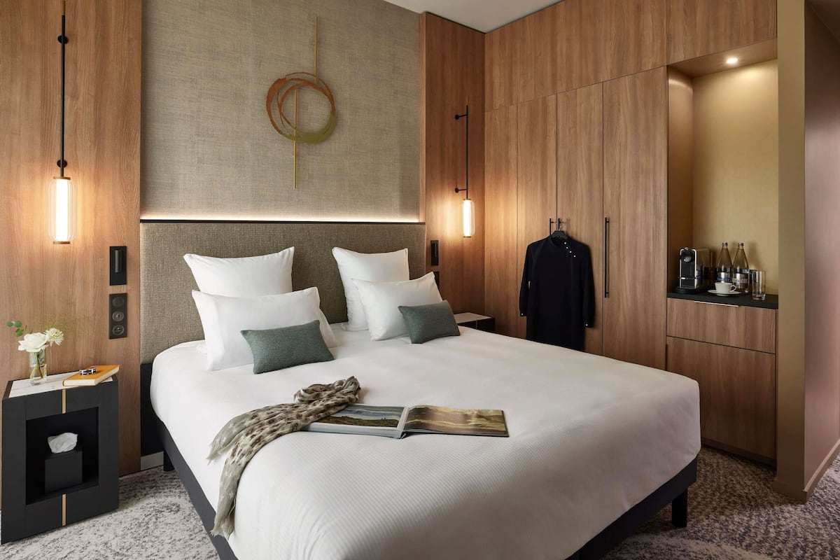 Ein modernes Hotelzimmer mit einem großen Bett, einem Nachttisch, einem Schrank und einem Spiegel.