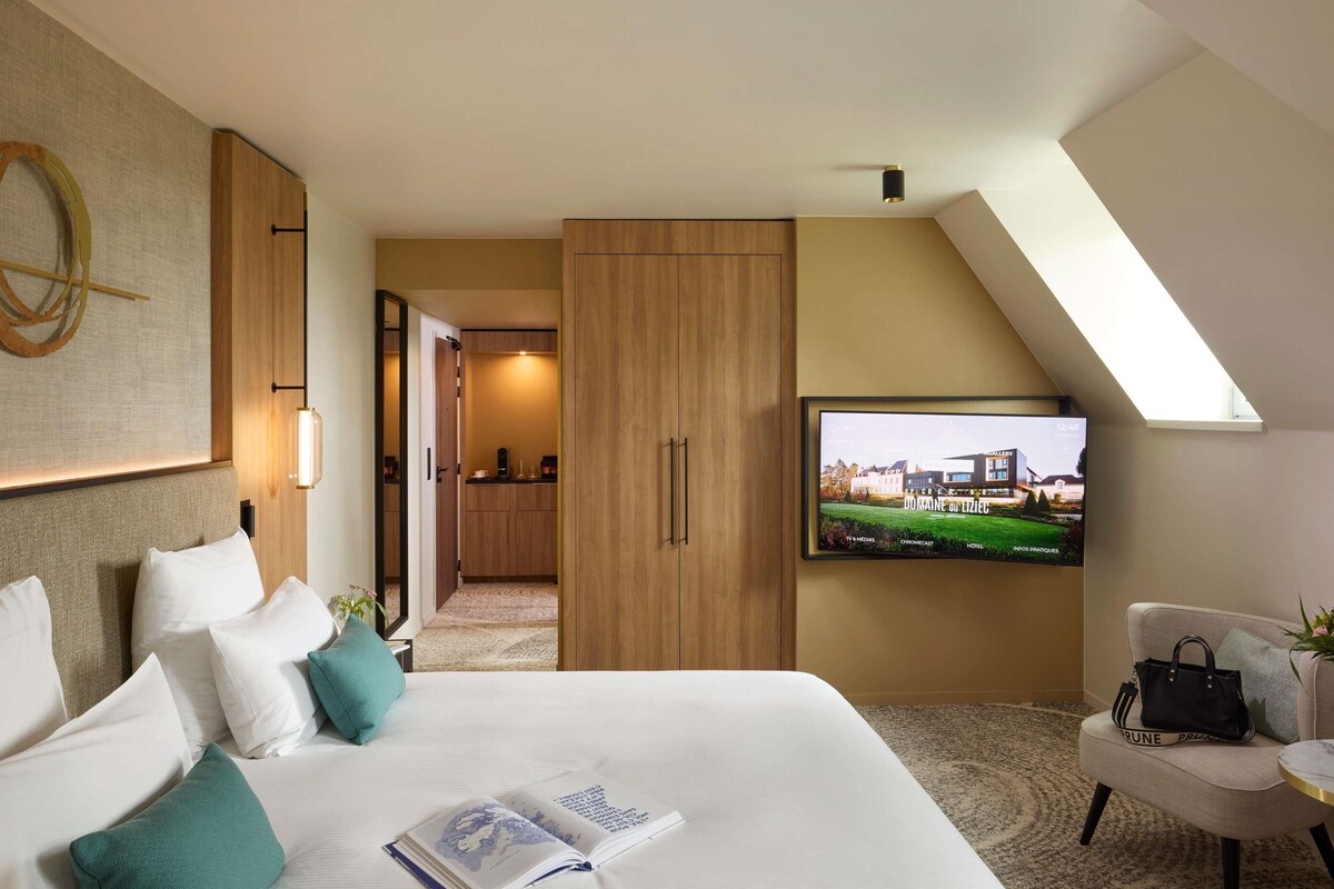 Une chambre d’hôtel équipée d’un lit, d’une télévision, d’un bureau et offrant une vue sur la façade de l’hôtel.