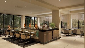 Una cocina moderna con una isla central, ventanas amplias y una zona de comedor con sillas y mesas.