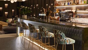 A bar area with a long counter, multiple stools, and a variety of bottles. - Domaine du Liziec Vannes - MGallery Collection (Vannes)