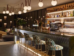 Un espace bar doté d’un long comptoir, de nombreux tabourets et d’une grande variété de bouteilles.