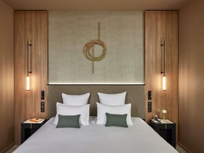 Une chambre d’hôtel avec un grand lit, deux tables de chevet, une œuvre d’art accrochée au mur et deux lampes murales.