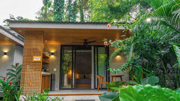 Ein modernes Haus mit einer Holterrasse, einem Deckenventilator und einer Schiebetür zu einer Sitzgelegenheit.