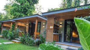 Ein modernes Haus mit überdachter Veranda, einem Holzzaun und einem gepflegten Garten.