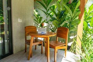 Juego de mesa y sillas de madera al aire libre, con una planta en maceta y un cartel sobre la mesa.