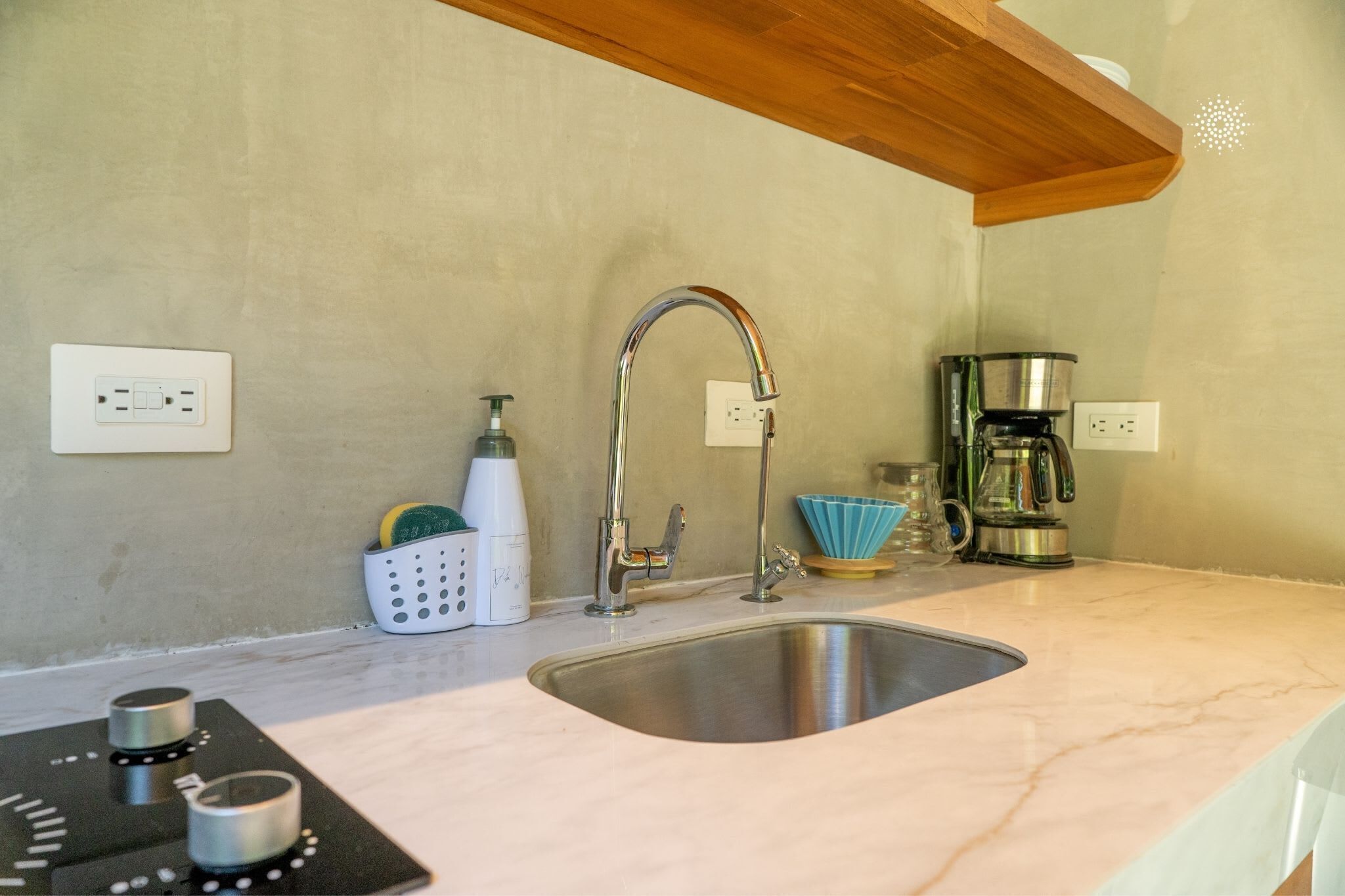A kitchen with a stainless steel sink, a coffee maker, and a soap dispenser on the countertop.