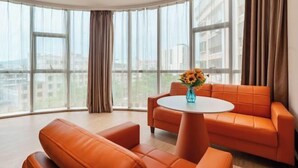 Een moderne kamer met een groot raam, een ronde tafel en oranje meubels.