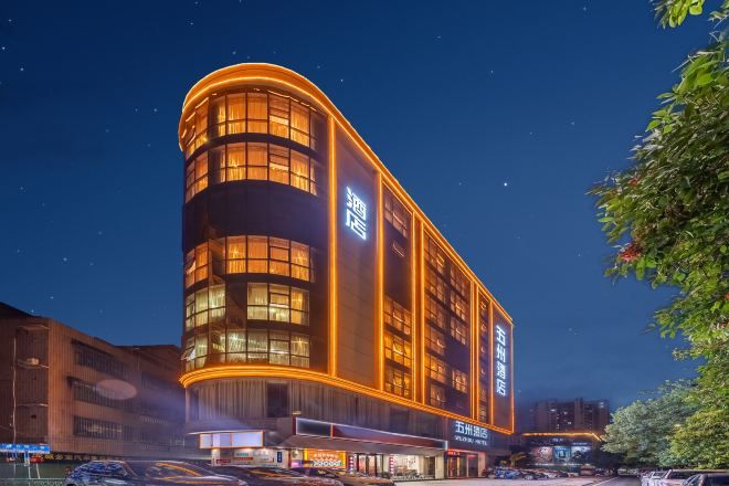 Ein Hotel mit einer geschwungenen Fassade, mehreren Etagen und beleuchteten Fenstern.