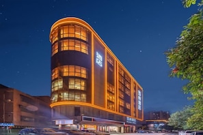 A hotel with a curved facade, multiple floors, and illuminated windows.