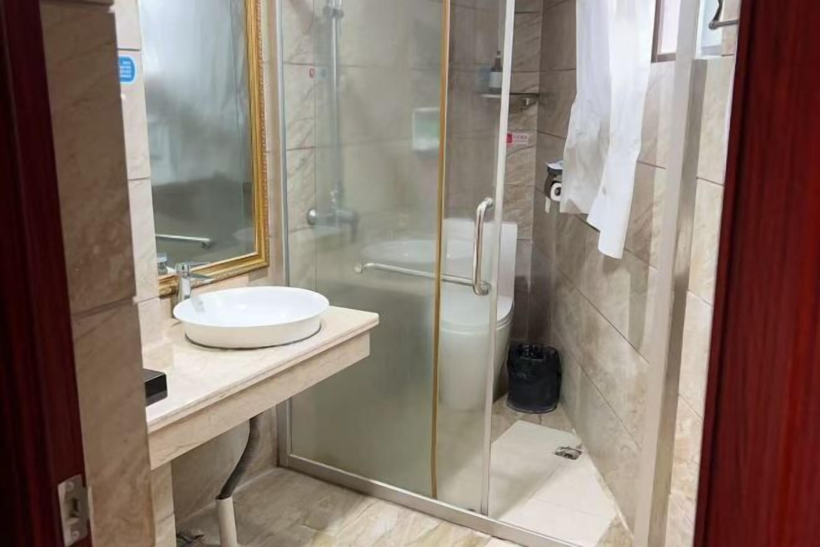 A bathroom with a glass-enclosed shower, a white sink, and a toilet.