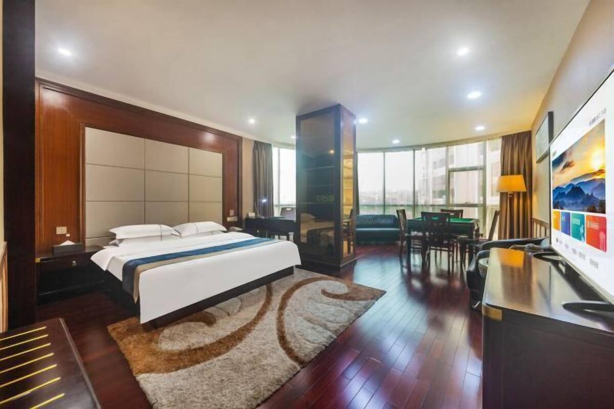Habitación de hotel con cama, escritorio, silla y un amplio ventanal.