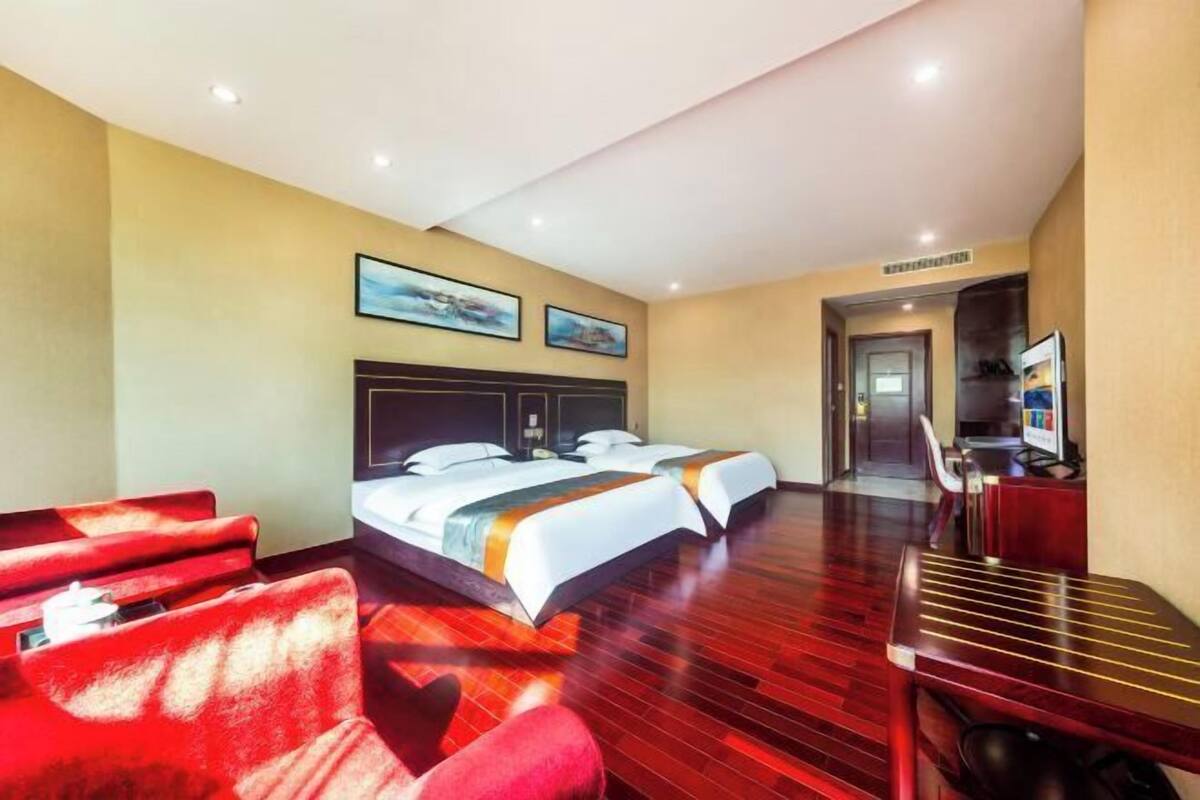 Habitación de hotel con dos camas, televisión y escritorio.