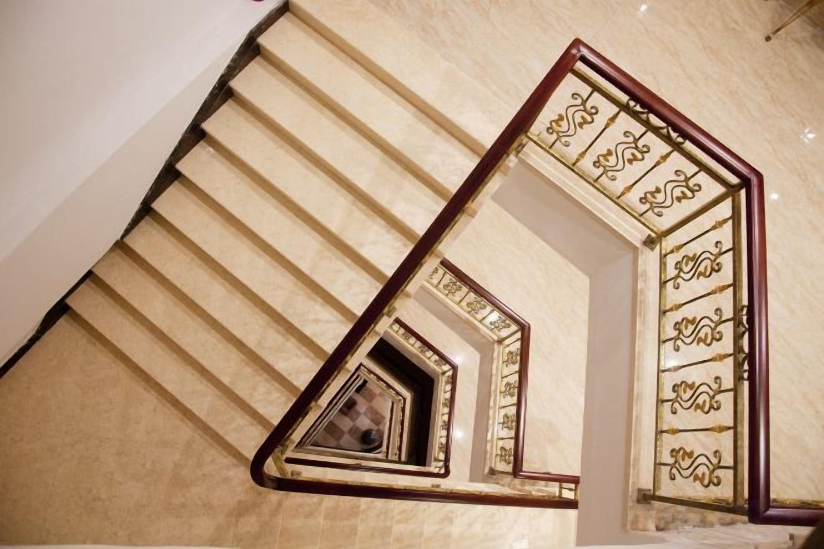 A spiral staircase with ornate metal railings and a geometric design on the walls.