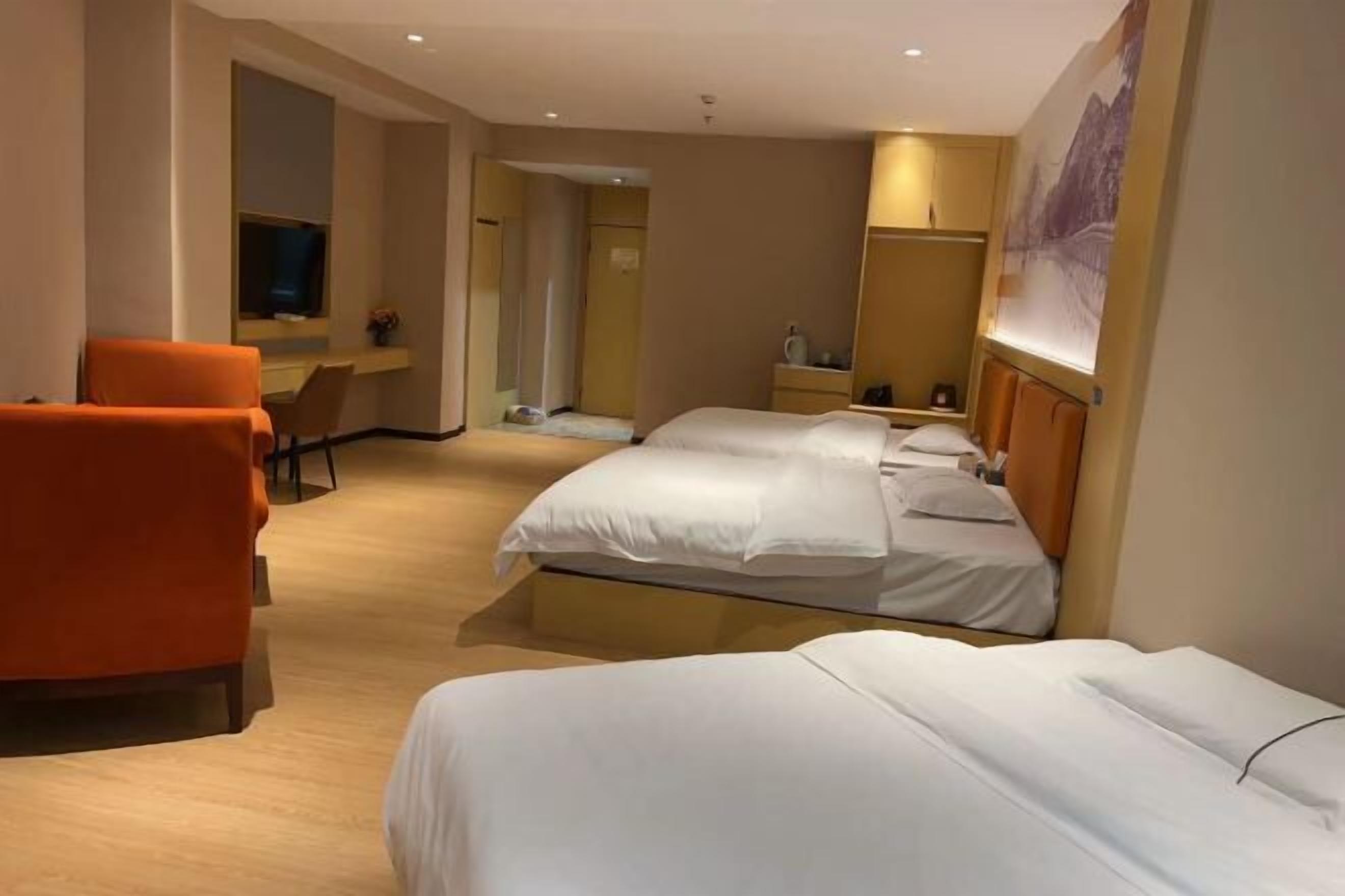 Ein Hotelzimmer mit zwei Betten, einem Schreibtisch, einem Stuhl und einem Fernseher.