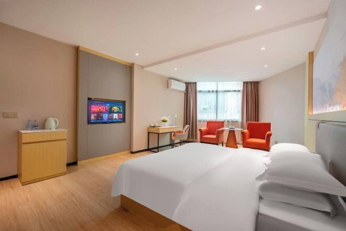 Una habitación de hotel con una cama grande, un escritorio con una silla, un televisor y una ventana con cortinas.