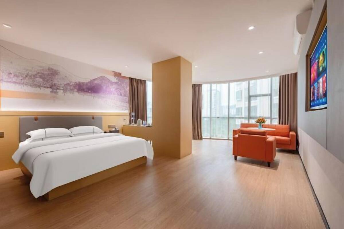 Una habitación de hotel moderna con una cama grande, un sofá y un televisor.
