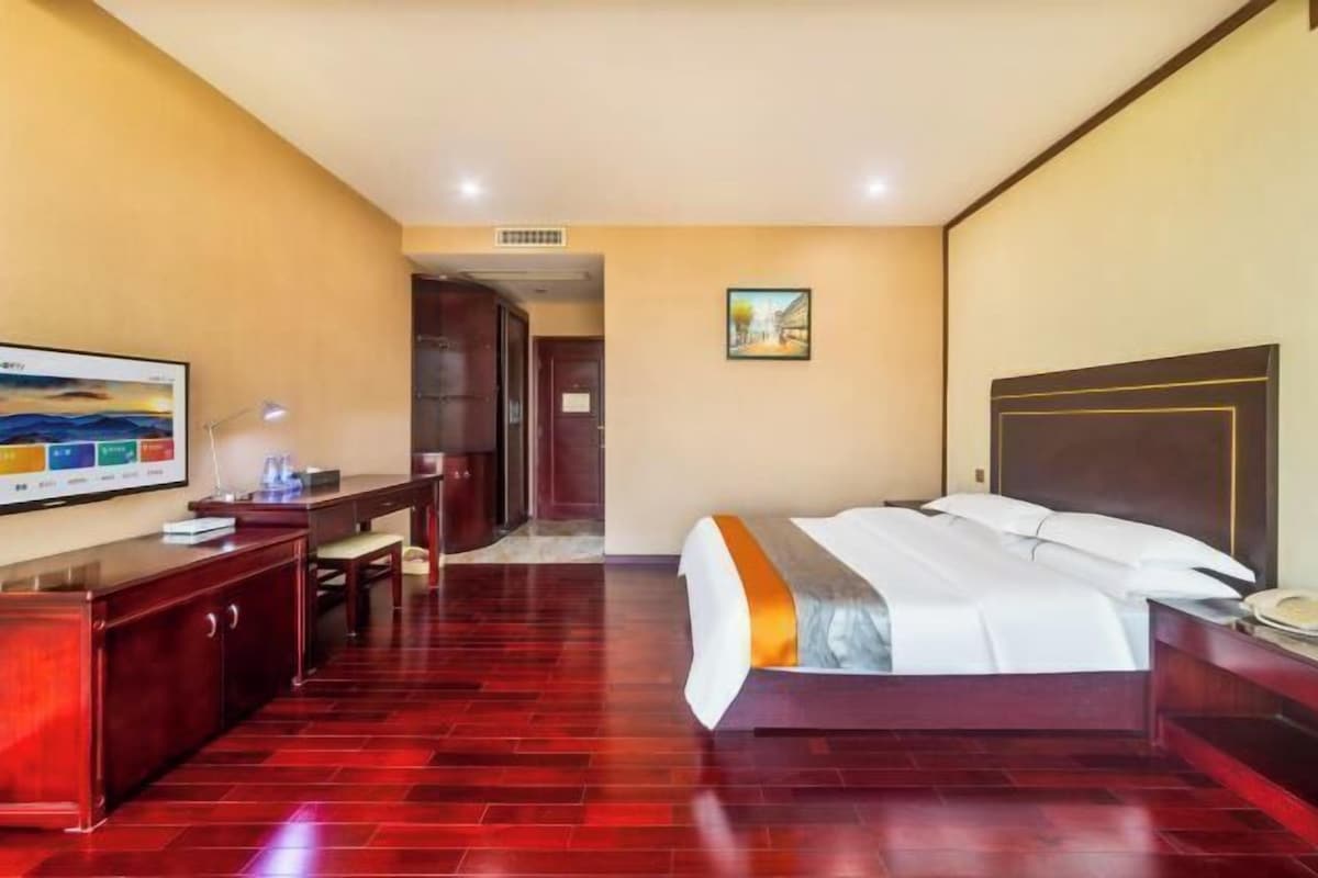 A hotel room with a bed, desk, chair, and a television on the wall.