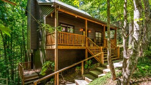 Eine Holzhütte mit einer Holzterrasse, einer Treppe und einer Veranda.