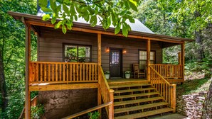 Eine Holzhütte mit Steinunterbau, einer Holzterrasse und einer Veranda mit Stufen zum Eingang.