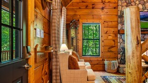 Ein gemütliches Blockhaus-Interieur mit einer Sofagarnitur, einer Holz-Wanduhren und einer Steinwand.
