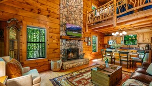 Ein Holzblockhaus-Interieur mit Kamin aus Stein, Holzmöbeln und einer Küchenzeile.