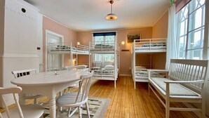 A room with bunk beds, a table with chairs, and a window with curtains. - Herrgård de luxe (Tävelsås)