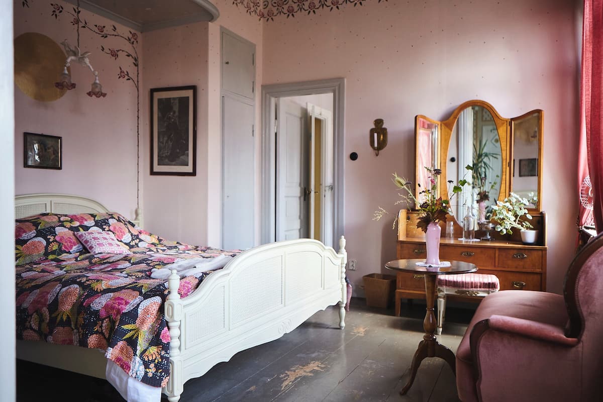 A bedroom with a bed, dresser, chair, and a mirror.