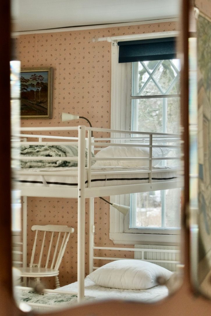 Une chambre avec un lit superposé, une fenêtre, une chaise et un radiateur.
