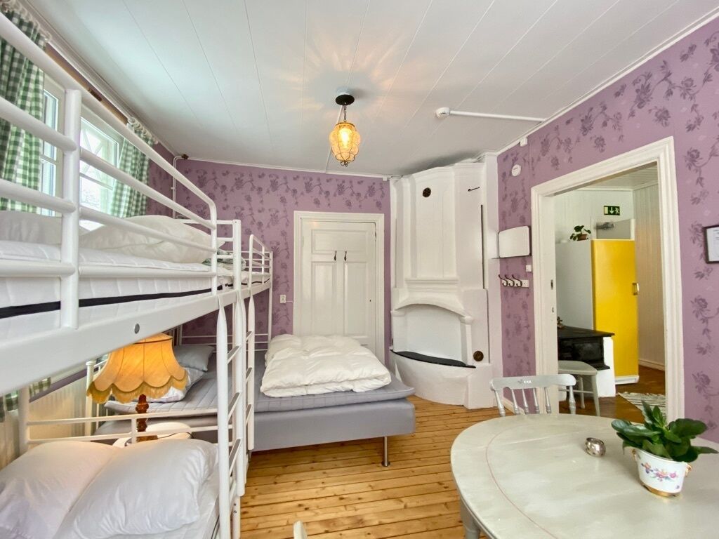 Ein Zimmer mit Stockbetten, einem kleinen Tisch, einer Lampe und einem Blumentopf.