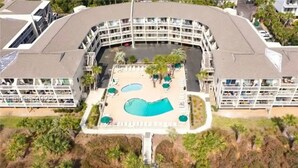 A modern hotel with a central courtyard featuring a swimming pool, lounge areas, and a landscaped garden. - Coligny Beachfront Villa w/Pool at The Breakers (Hilton Head Island)